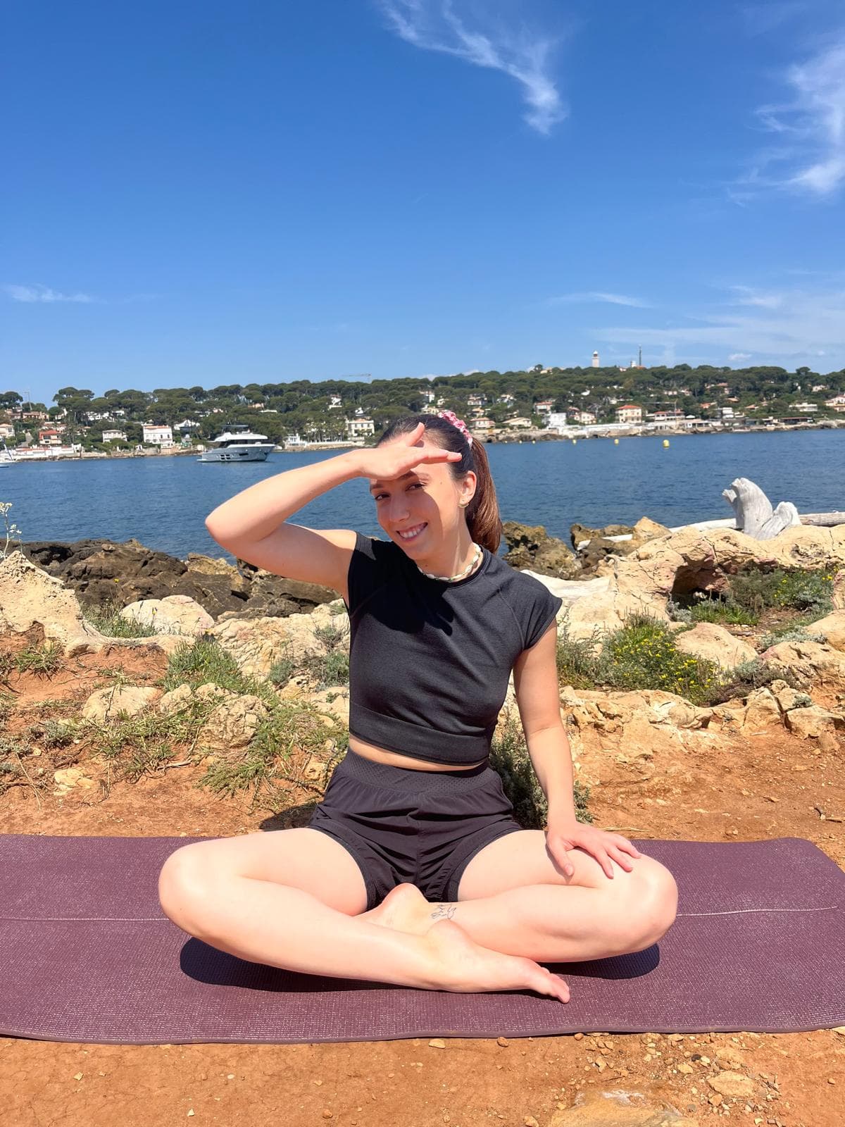 Jess assise sur un tapis de yoga face à la mer